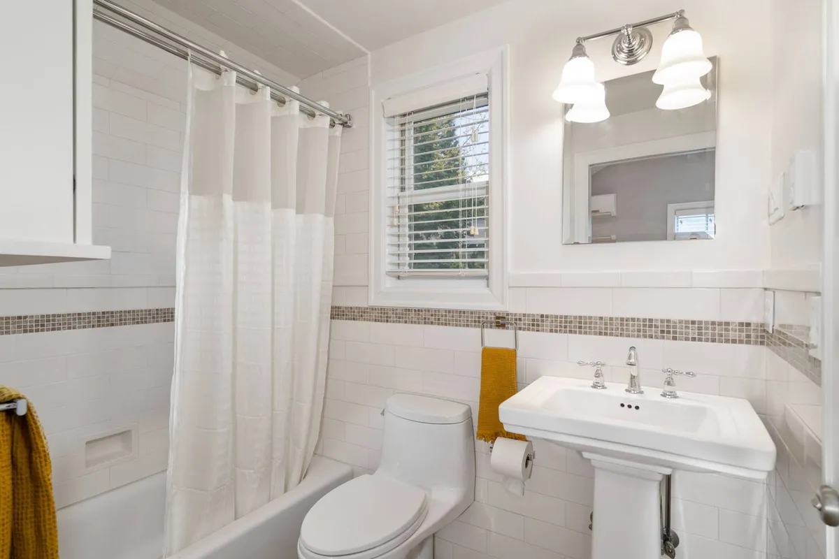 A thoughtfully appointed bathroom featuring a modern bathtub, sink, large window, and elegant lighting. Towels are neatly arranged, and the space feels serene, offering both revitalizing showers and calming baths in a spa-like setting.